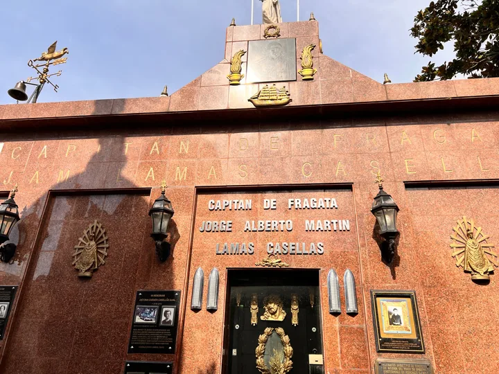 Red granite tomb facade of a naval captain, gilded lettering, lanterns and bronze memorial plaques