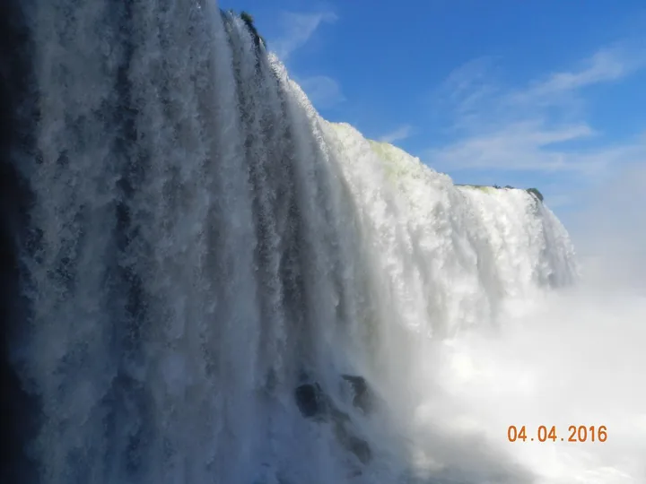 Close view of a sheer curtain of white water plunging into mist against clear blue sky