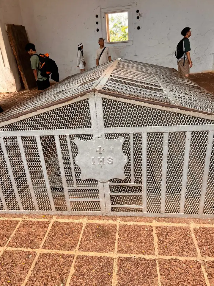 Empty stone grave under a wire cage marked IHS inside the roofless St Paul’s Church, Melaka